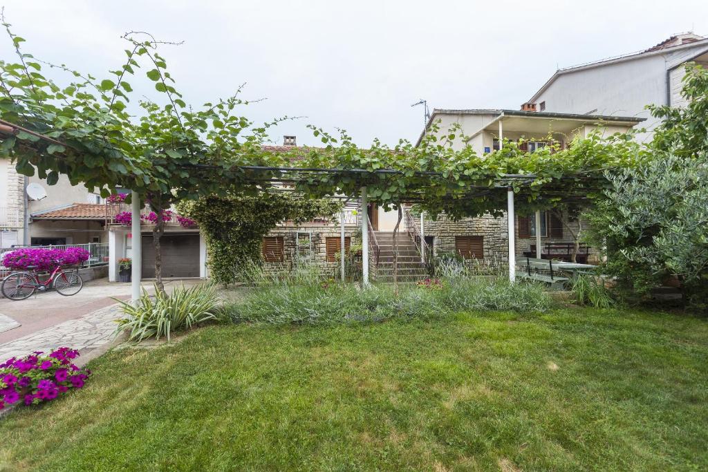 una casa con un giardino verde con fiori viola di Apartments with a parking space Fazana - 18334 a Fažana
