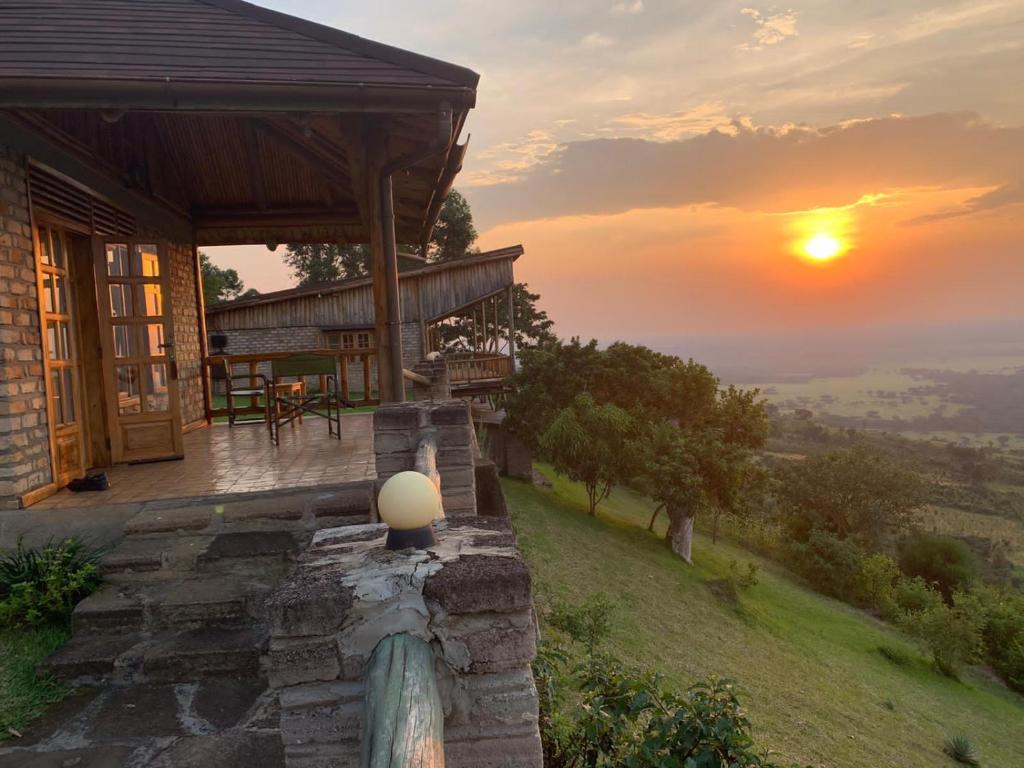 a house on a hill with the sunset in the background at Rift Valley Game Lodge Rubirizi in Katara