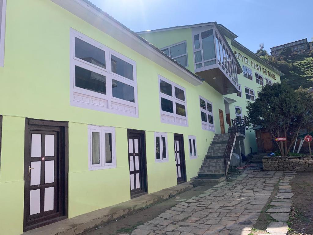 een geel en groen gebouw met een stenen straat bij Hotel Camp de Base in Namche