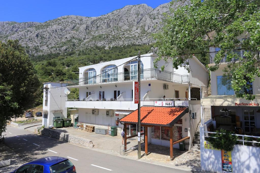 a white building with an orange roof in front of a mountain at Apartments by the sea Zivogosce - Porat, Makarska - 18218 in Igrane