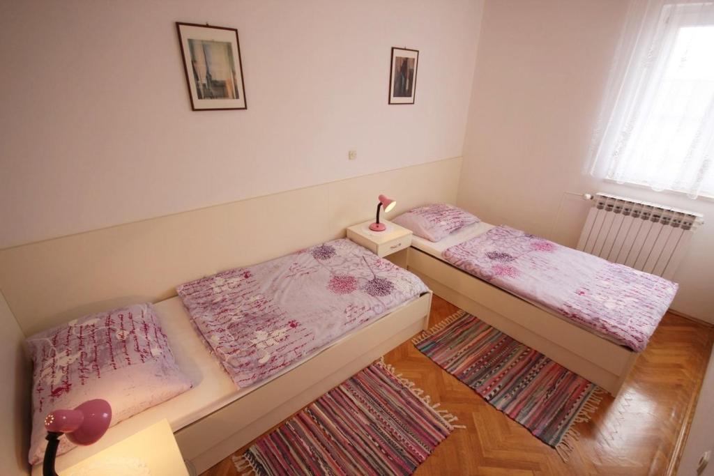 2 łóżka pojedyncze w pokoju z dywanem w obiekcie Apartments by the sea Vir - 18514 w mieście Vir
