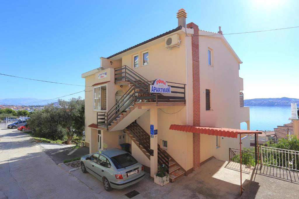 een gebouw waar een auto voor geparkeerd staat bij Apartments by the sea Seget Donji, Trogir - 18488 in Trogir