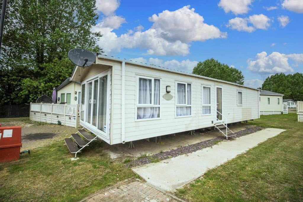 Casa móvil blanca con ventanas en un patio en Modern 6 Berth Caravan At Highfield Grange In Essex Ref 26609p en Clacton-on-Sea