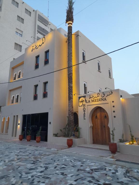 un hotel con una palmera frente a un edificio en HÔTEL DE LA MEDINA, en Nouakchott