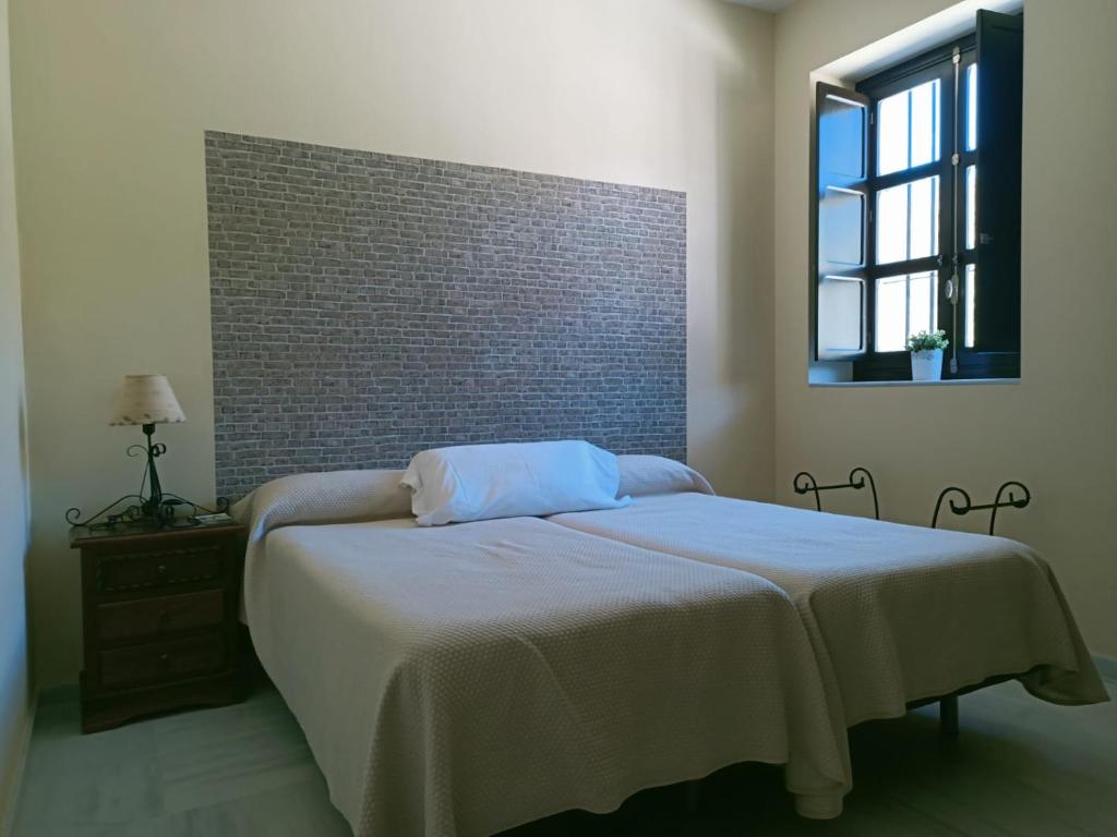 Un dormitorio con una cama y una pared de ladrillo. en Estación de Coripe, en Coripe
