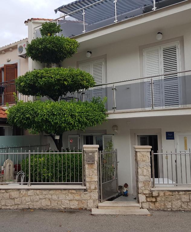 a house with a gate and a tree in front of it at Rooms &amp; Apartments Barišić in Mlini