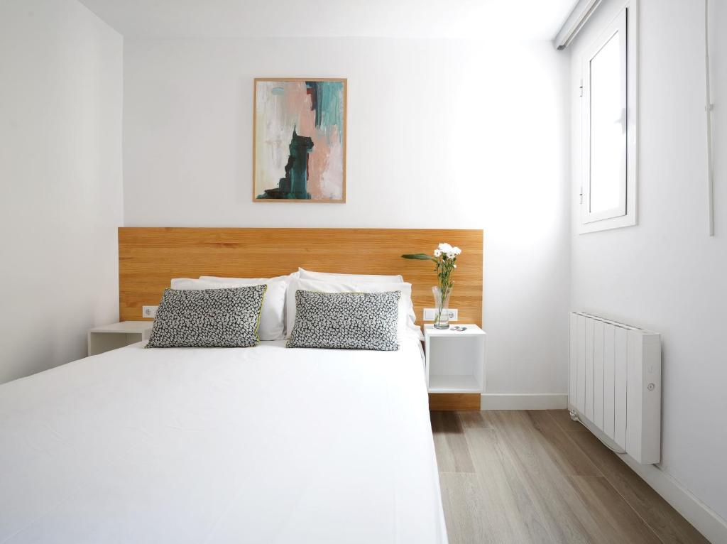biała sypialnia z dużym białym łóżkiem z 2 poduszkami w obiekcie numa I Calid Apartments w mieście Hospitalet de Llobregat