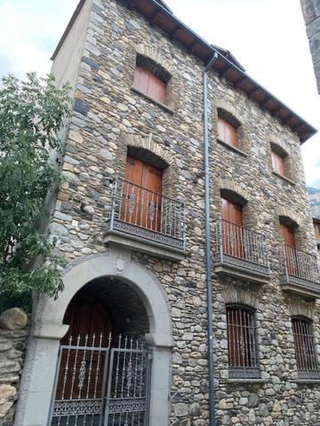 un alto edificio in pietra con finestre e cancello di Casa Conchita de Benasque a Benasque