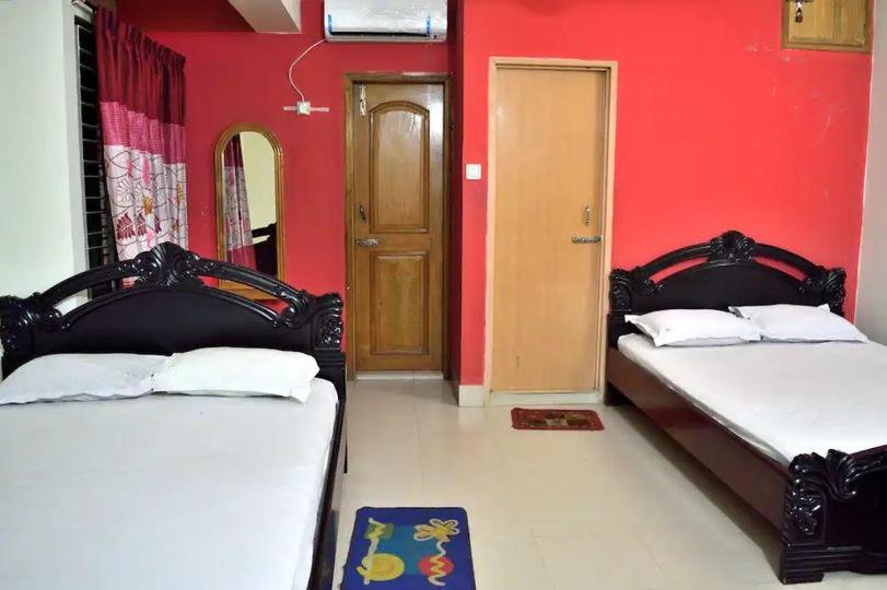 - 2 lits dans une chambre dotée d'un mur rouge dans l'établissement Sea Breeze Resort, à Cox's Bazar