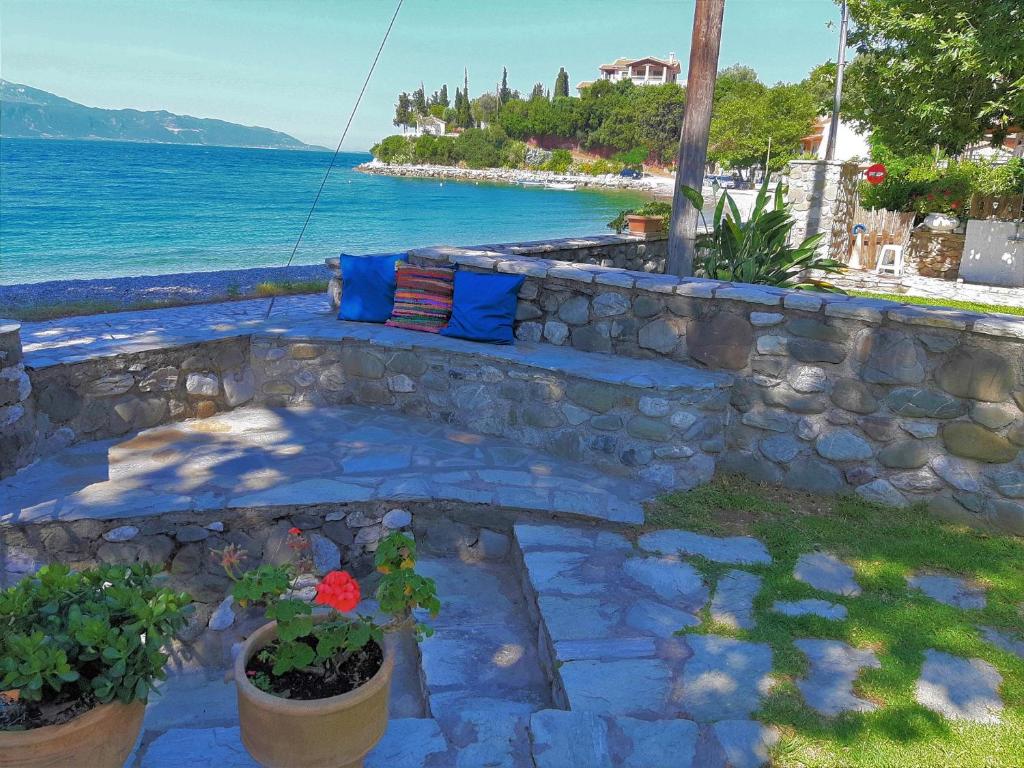 Karaḯskos的住宿－Beachfront Skaloma Villa，海边的石头长凳,上面有蓝色和红色的枕头