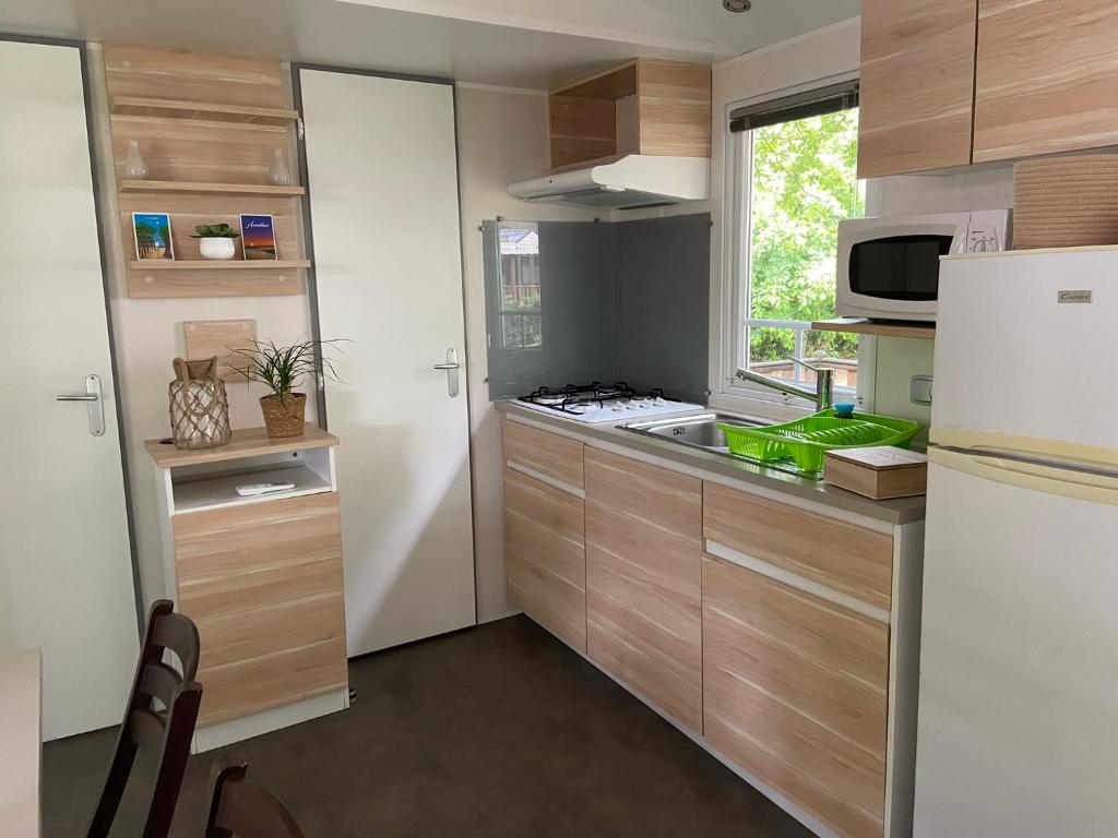 una cucina con armadi in legno e frigorifero bianco di MOBIL HOME Climatisé G058 ad Aureilhan