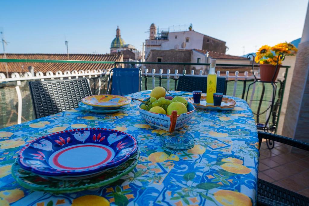 a table with plates and a bowl of fruit on a balcony at CASA TERESA NEL CENTRO DI VIETRI in Vietri