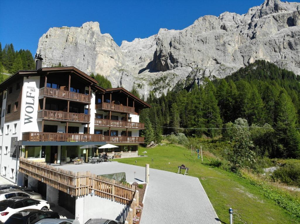 a hotel with cars parked in front of a mountain at Hotel Wolf in Selva di Val Gardena