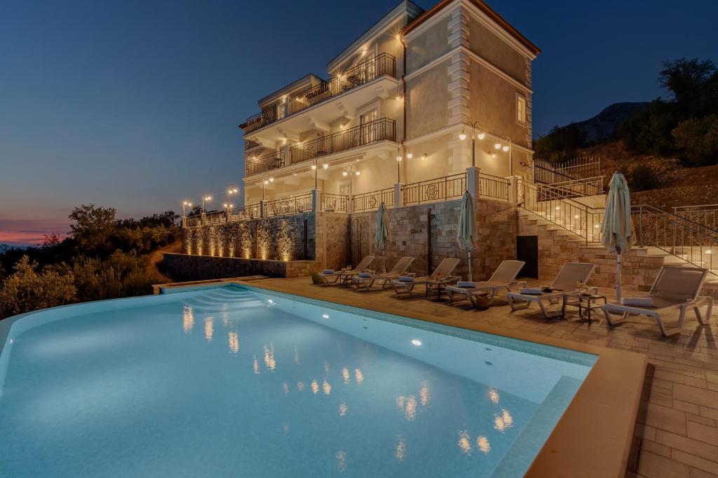 a villa with a swimming pool in front of a building at Heritage Hotel Liberan in Podgora
