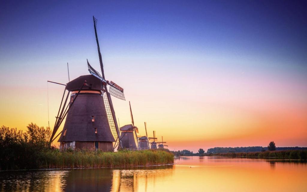 un molino de viento en medio de un río al atardecer en B&B Oostzomerland, en Mijnsheerenland