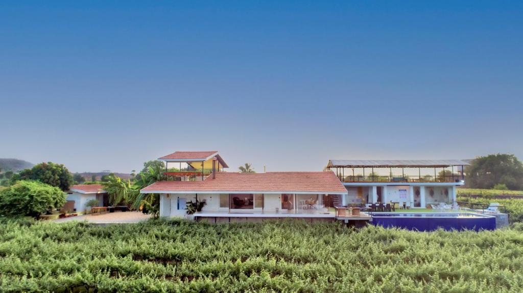 a house in the middle of a field at SaffronStays Onellaa, Nashik - infinity pool villa surrounded by a vineyard in Nashik