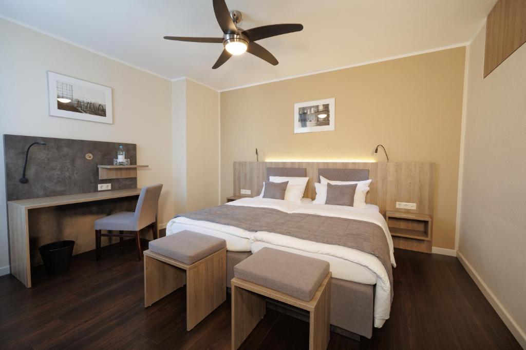 a bedroom with a large bed with a ceiling fan at Hotel Jellentrup in Münster