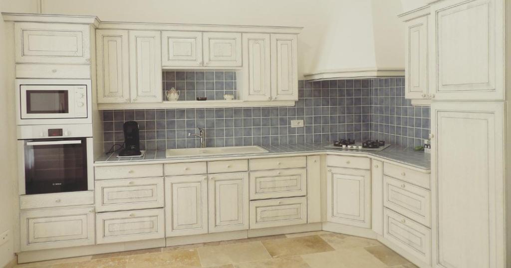 una cocina blanca con armarios blancos y fregadero en Gîte Maison Necty en Auvillar