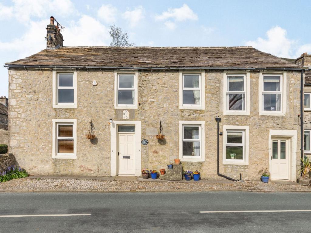 an old stone house with white doors and windows at Anglers Cottage in Skipton