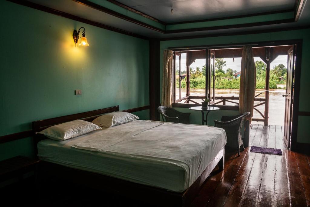 a bedroom with a bed and a large window at Nongsak Riverside Guesthouse & Nongsak Guesthouse in Ban Khon