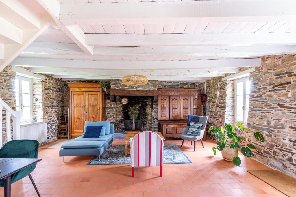 een woonkamer met meubels en een stenen muur bij La Villauvert - Cottage in Saint-Martin-sur-Oust