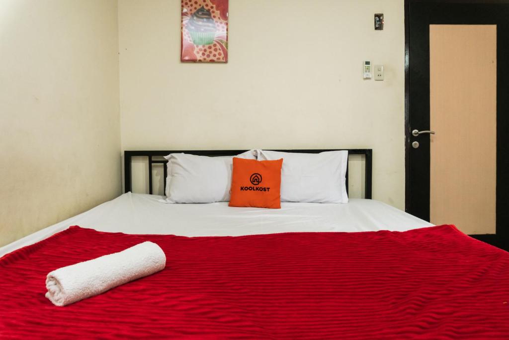een bed met een rode deken en een tas erop bij KoolKost near State Museum of North Sumatera Medan in Medan