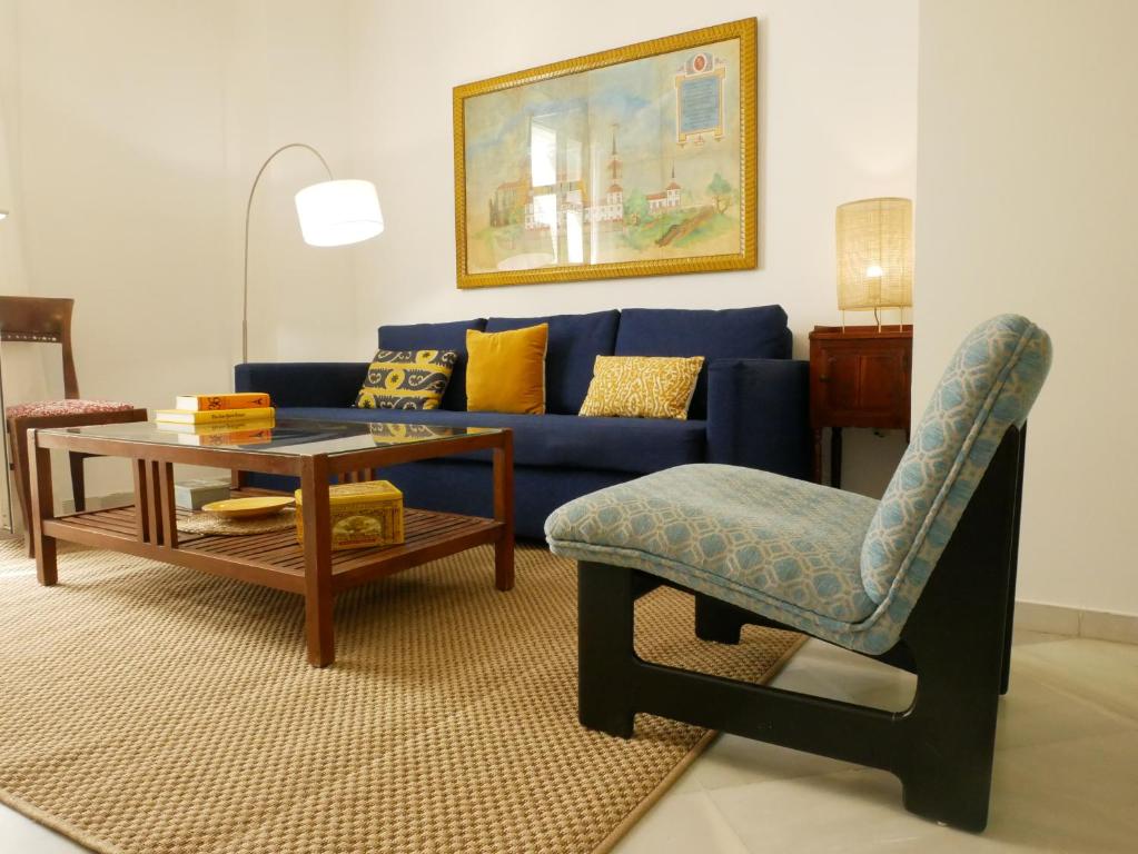 a living room with a blue couch and a table and a chair at Sierpes 50 in Seville