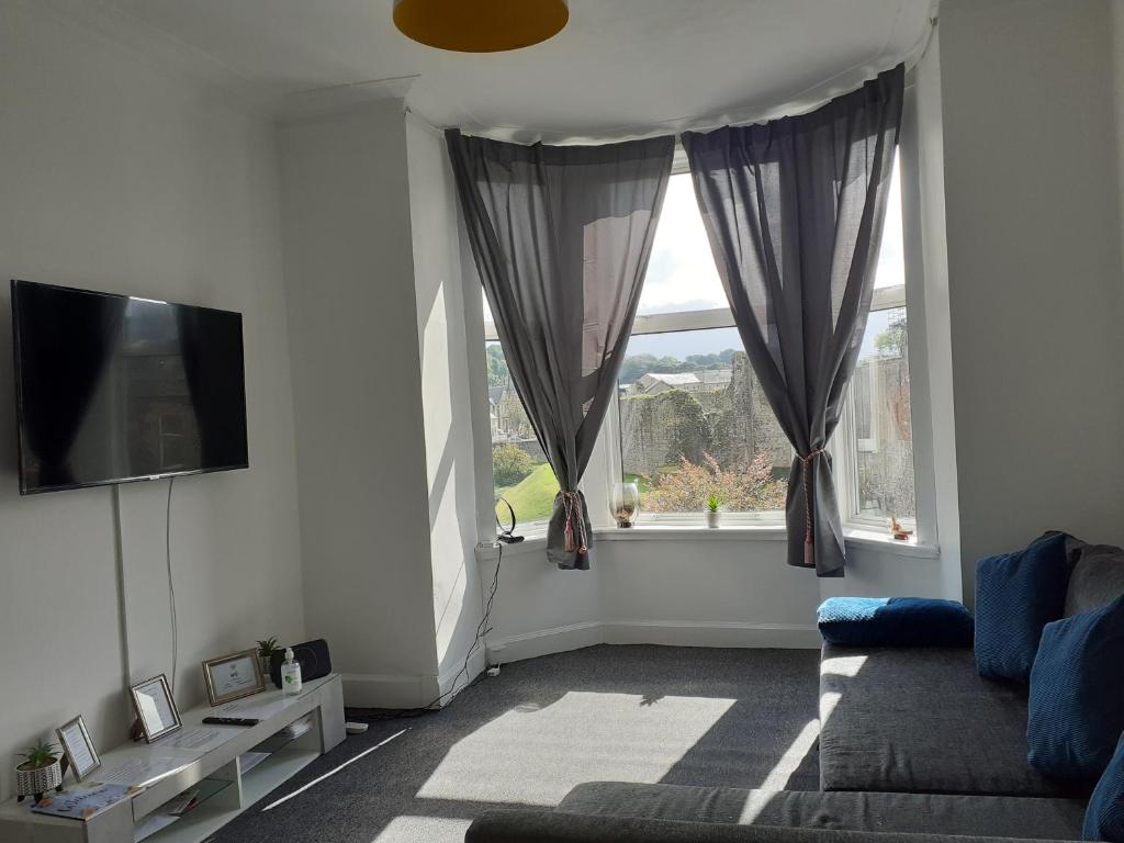 un soggiorno con divano e 2 finestre di Castleview is a lovely flat in a listed building a Rothesay