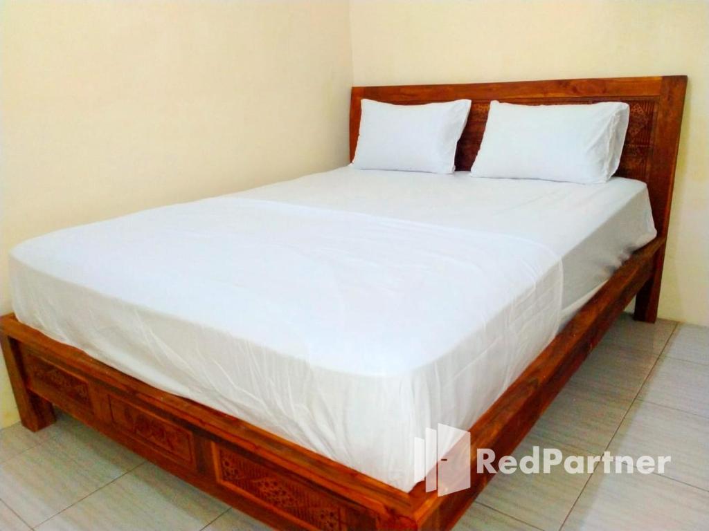 a wooden bed with white sheets and pillows at Navisha Guest House Syariah near Exit Tol Batang RedPartner in Pekalongan