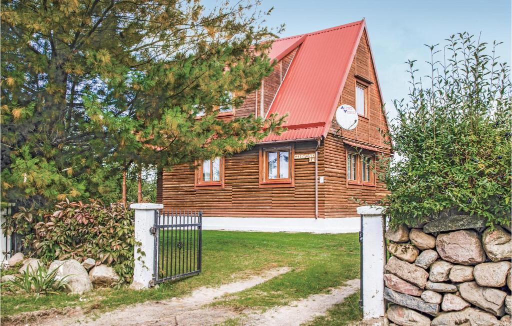 a wooden house with a red roof and a gate at Awesome Home In Mragowo With Kitchen in Kosewo