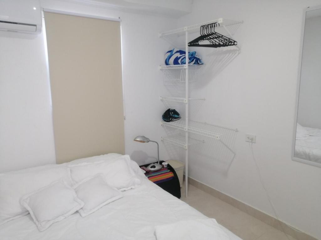biała sypialnia z łóżkiem i szafą w obiekcie Hermoso Apartaestudio, privado, acogedor, super aseado, excelente ubicación! w mieście Cartagena de Indias