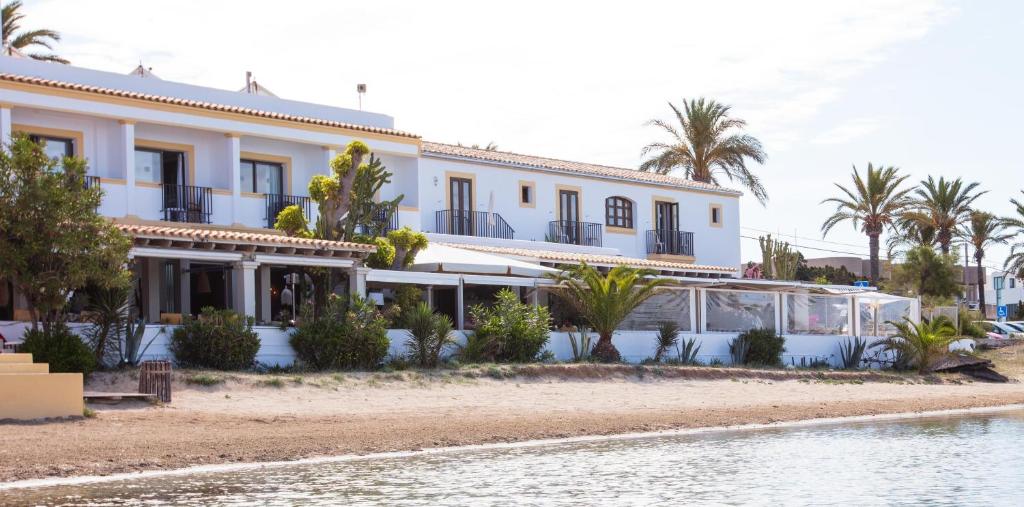 a building on the shore of a body of water at Hostal la Savina in La Savina