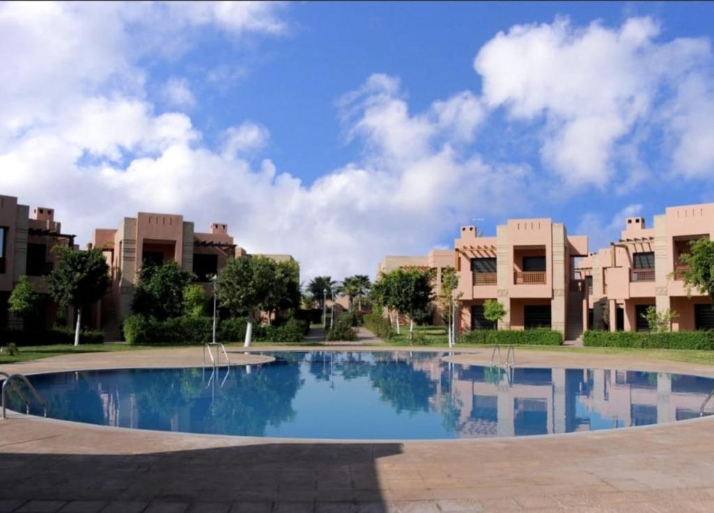 een groot zwembad met gebouwen op de achtergrond bij Bel Appartement dans une résidence Fermée avec piscine in Marrakesh