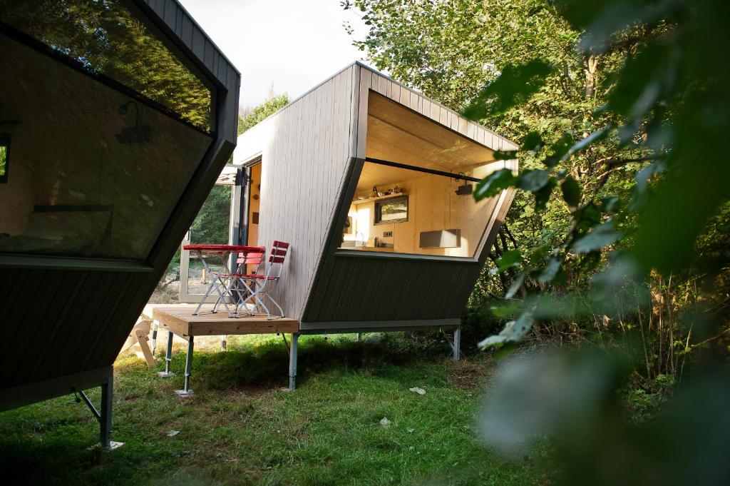 una pequeña casa con una silla roja en el patio en Sleep Space 22 - Green Tiny Village Harz, en Osterode