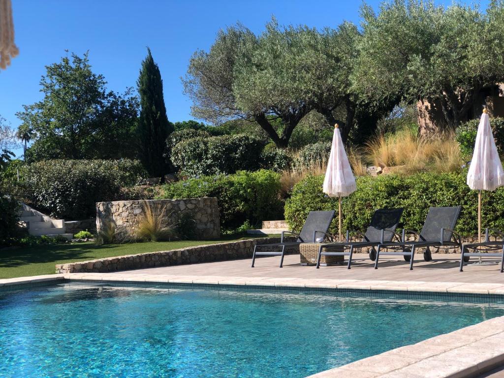 a swimming pool with two umbrellas and chairs next to a swimming pool at Auberge de l'Oumède in Saint-Tropez
