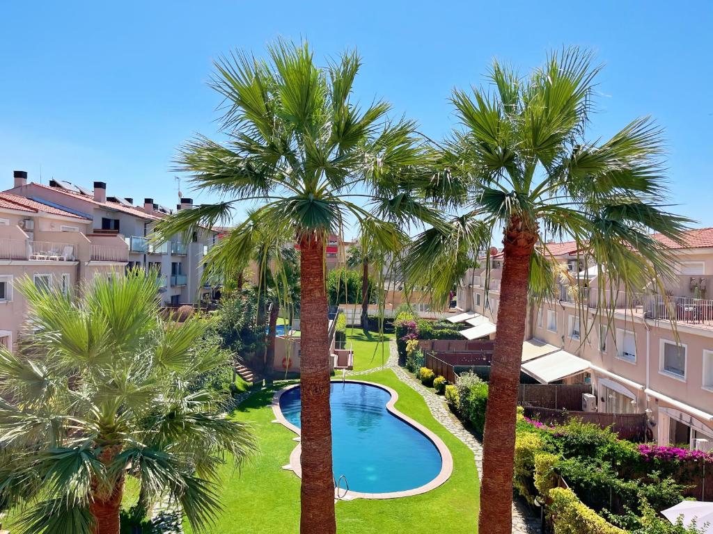 uma vista aérea de um resort com palmeiras e uma piscina em Cheerful Townhouse Center Sitges 5 bedrooms Pool and Terrace em Sitges
