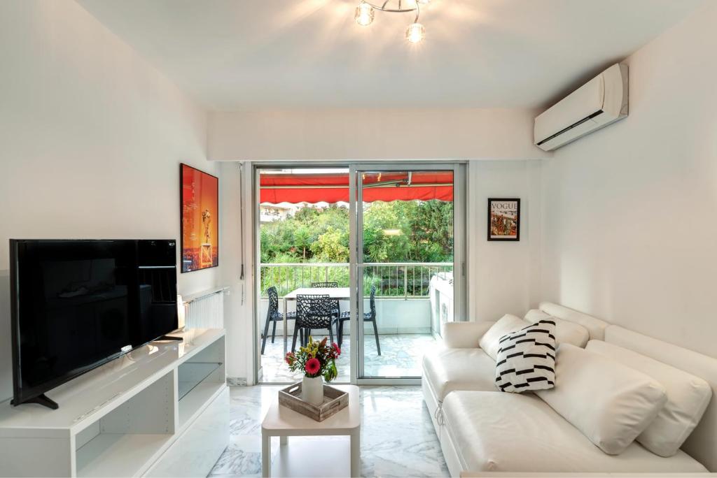 uma sala de estar com um sofá branco e uma televisão em Appartement 2 pièces au calme proche Martinez avec parking privé em Cannes