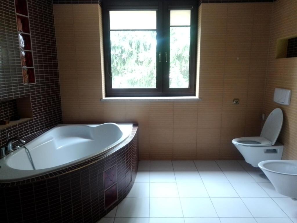 łazienka z wanną, toaletą i oknem w obiekcie Willa Mateusza w mieście Sandomierz