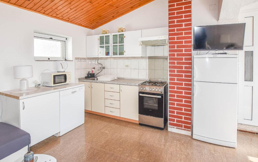 a kitchen with white appliances and a brick wall at Apartments Ante in Pakoštane