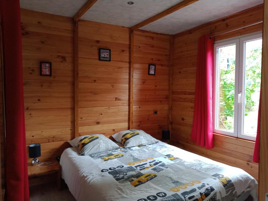 een slaapkamer met een bed in een kamer met houten wanden bij Chalet du Sanglier in Rancennes