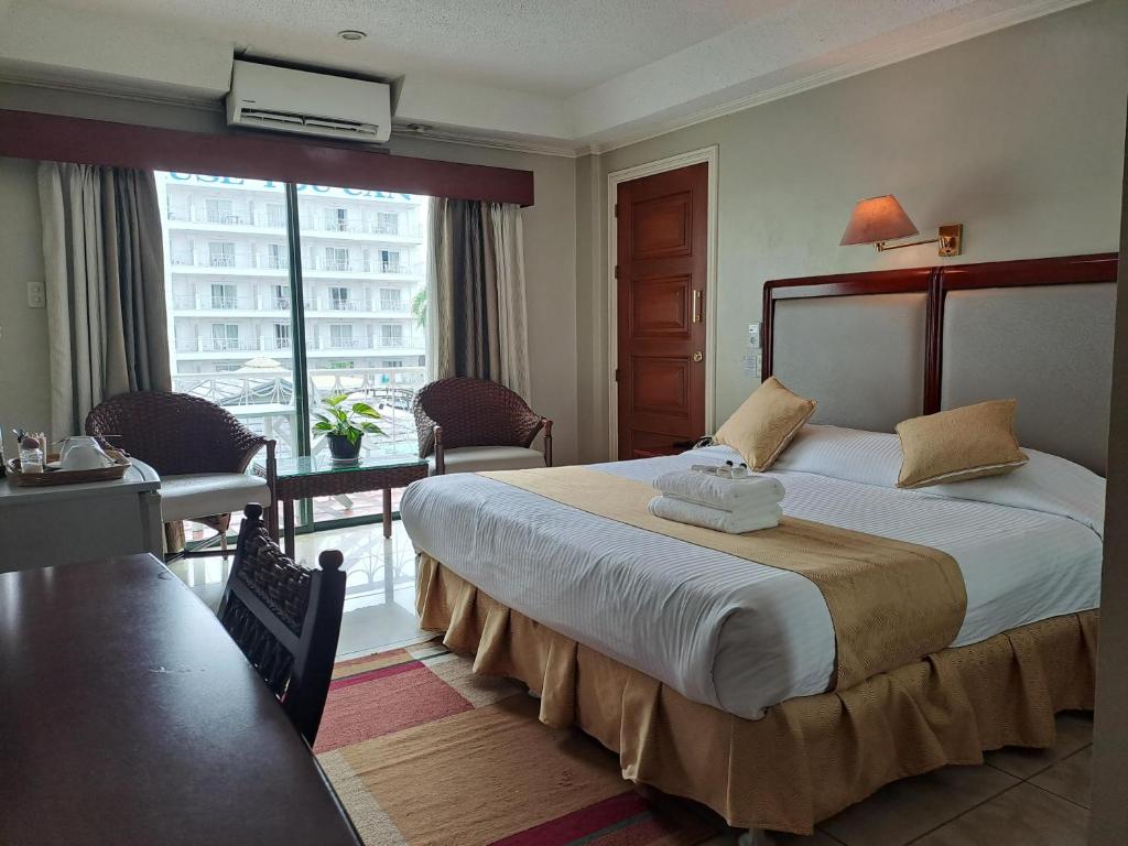 アンヘレスにあるワイルド オーキッド リゾートの大きなベッドとデスクが備わるホテルルームです。
