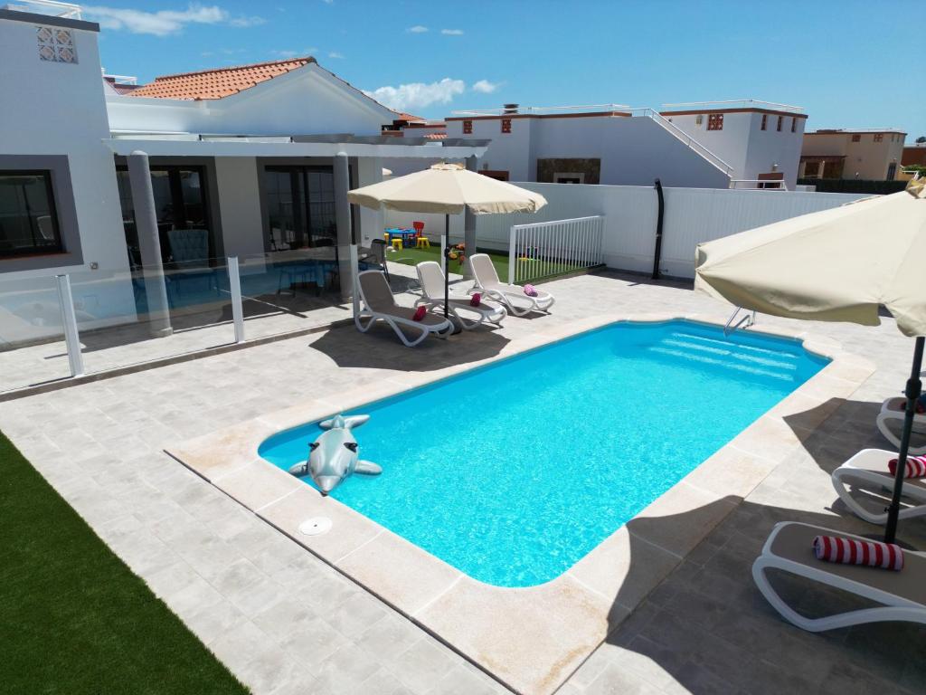 una piscina en un patio con sillas y sombrillas en Ideal for family holidays, near beach and golf- Casa James, en La Guirra