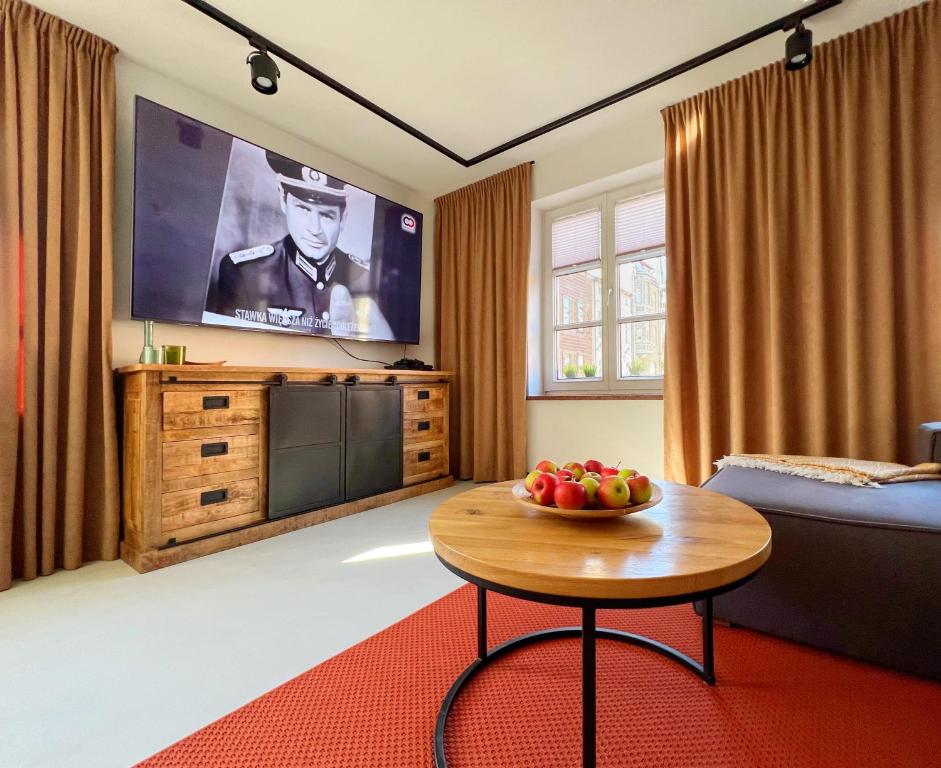a living room with a table and a tv at Apartament Hansa Klossa in Olsztyn