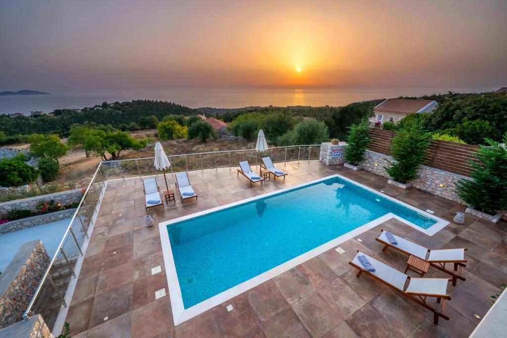 a villa with a swimming pool and a sunset at Villa Cleopatra Fiskardo in Fiskardho