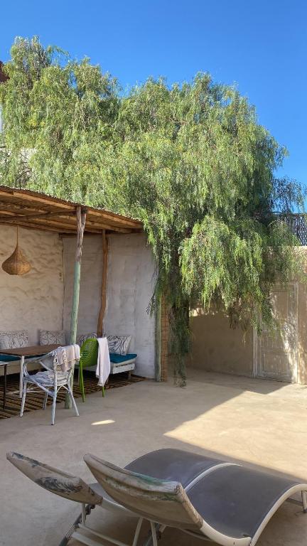un patio con tavolo, sedie e un albero di Suite BELDI, La Maison des paons a Sidi Kaouki