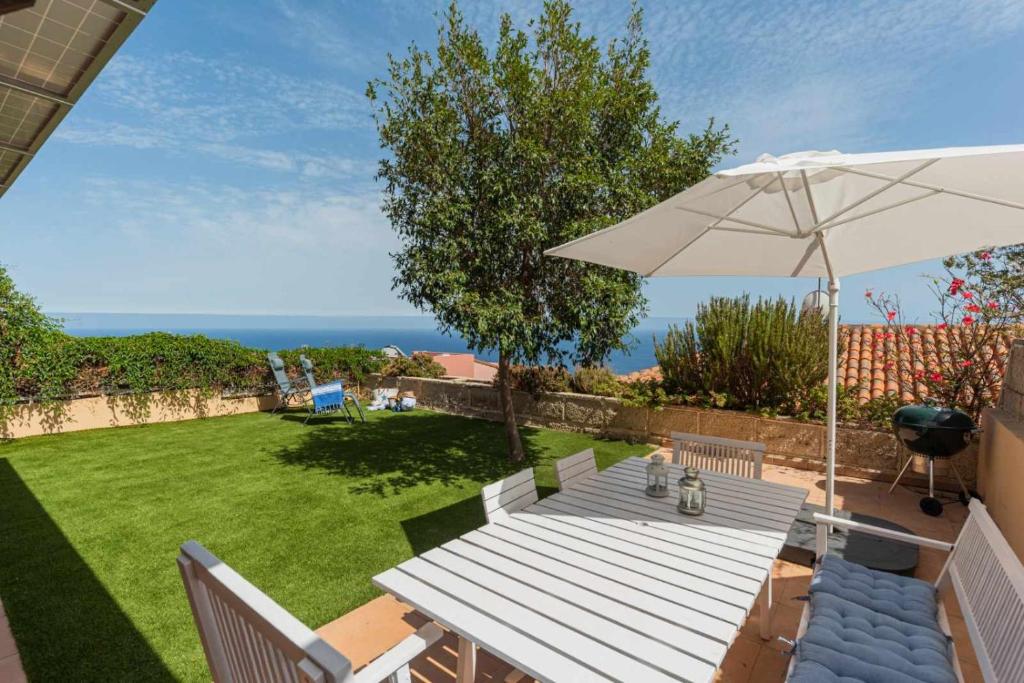 a wooden table with an umbrella and a lawn at Luxury Villa y Ocean View in Santa Cruz de Tenerife