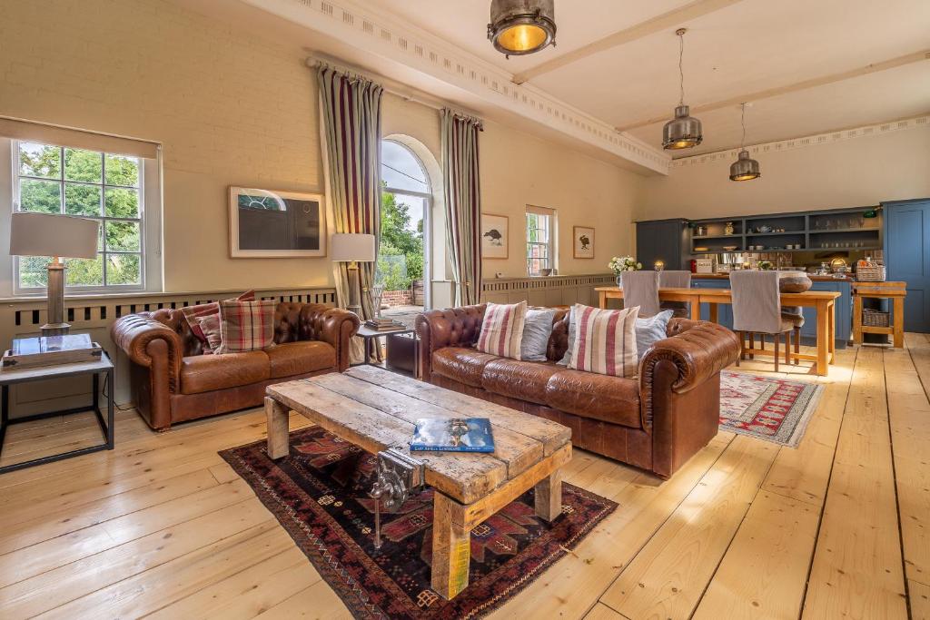 sala de estar con muebles de cuero y mesa en Stunning luxury cottage in historic country estate - Belchamp Hall Stables, en Belchamp Otten