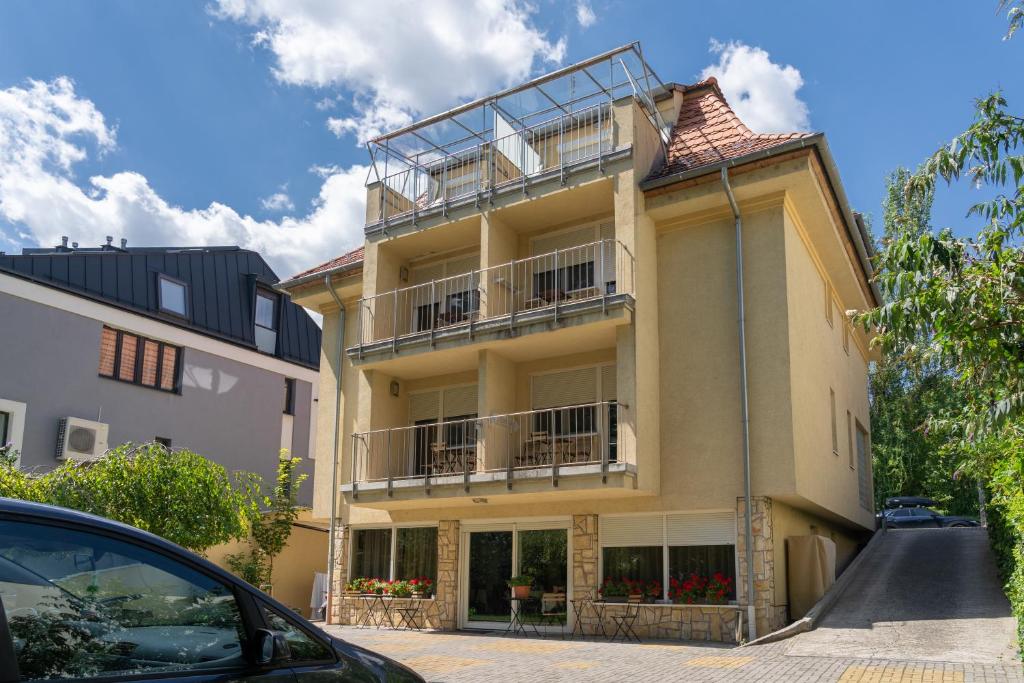 un bâtiment avec balcon et une voiture garée devant. dans l'établissement BALATONAIR Vendégház, à Balatonfüred