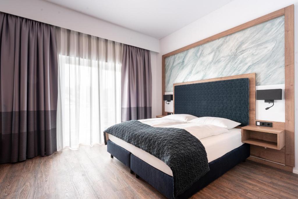 a bedroom with a large bed and a large window at Hotel Traunfall in Viecht