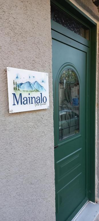 a sign on the side of a building with a green door at Mainalo View House in Vitina